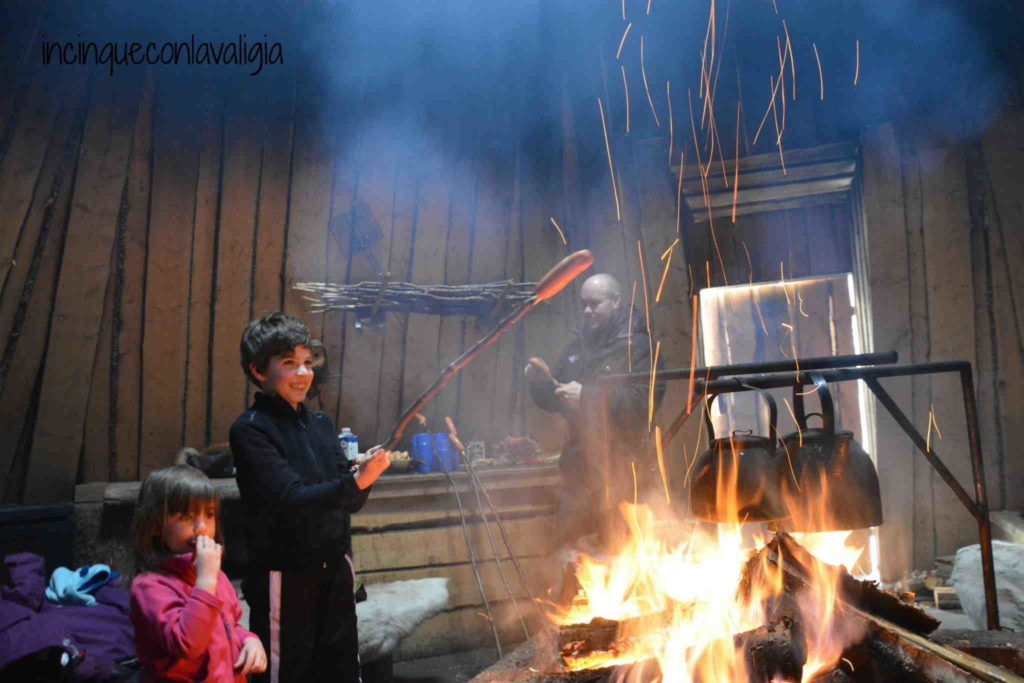 Grigliare salsicce sul fuoco nella kota Lapponia con bambini grigliare salsicce nella Kota